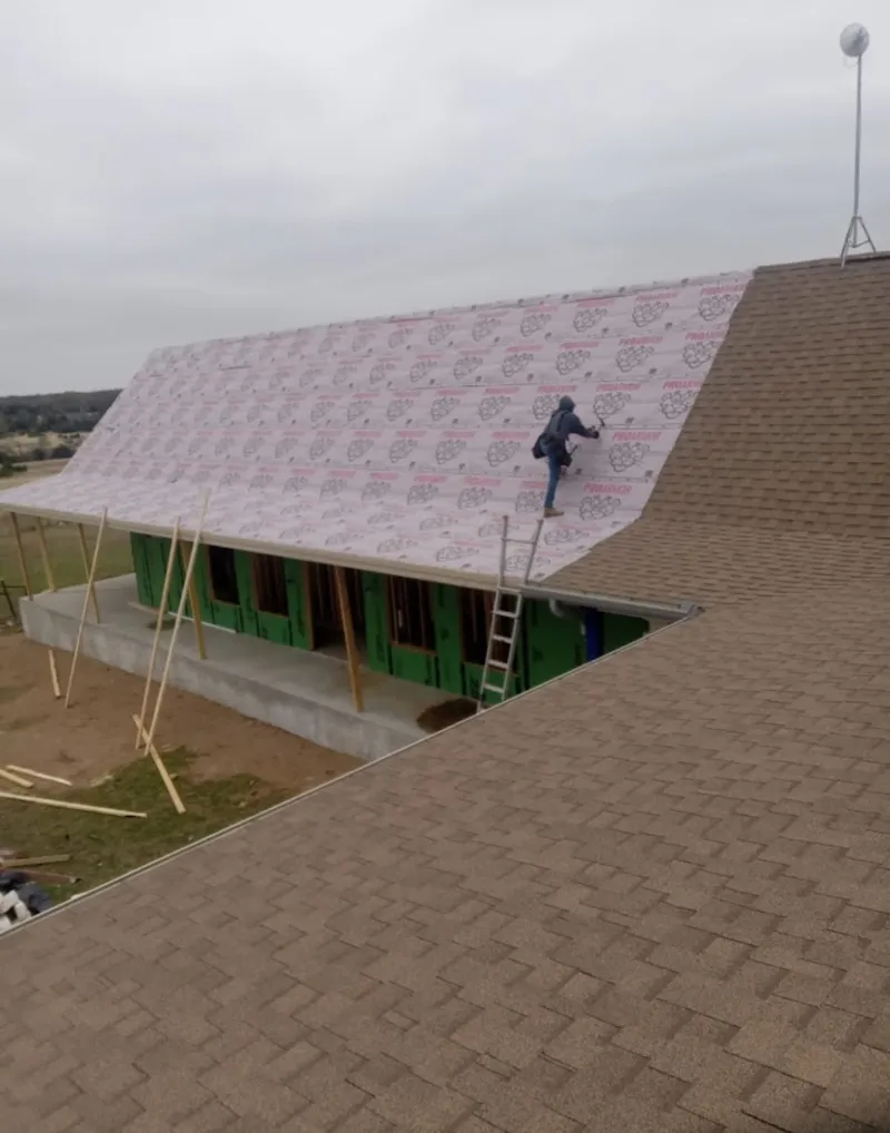 Worker preparing underlayment for a metal roof installation in Rostraver